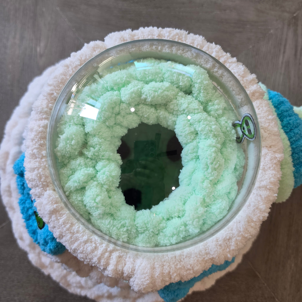 Top-down view of UFO pet cave showing clear acrylic dome and soft mint green chunky knit interior with center opening — handmade small animal hideaway by Chunky Knitter"