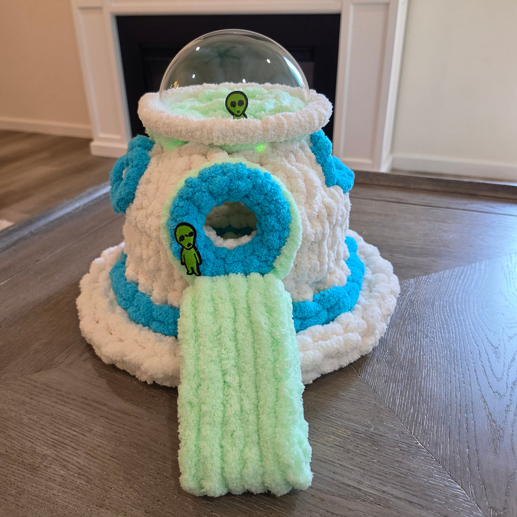 "Handmade chunky knit UFO pet cave in white and turquoise with clear dome top, green LED lights, alien embellishments, and mint green removable ramp — ferret and sugar glider hideaway by Chunky Knitter"