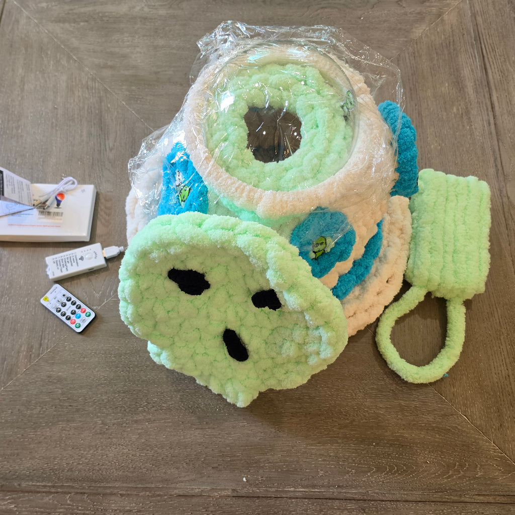 "Angled view of handmade UFO pet cave showing clear dome top, turquoise chunky knit accents, alien sembellishments, and mint green entry ramp — cozy hideaway for ferrets and sugar gliders" 